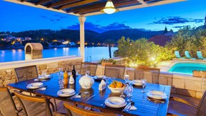 Uma área de refeições ao ar livre com vista para um lago e montanhas ao entardecer.