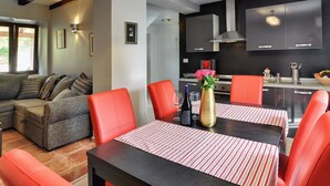 Un salon moderne avec un canapé, des fauteuils rouges et une table à manger recouverte de nappes à rayures.