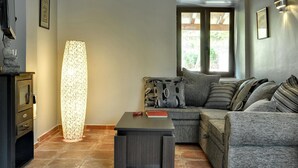Un salon chaleureux avec un canapé d’angle, un grand lampadaire et une petite table.