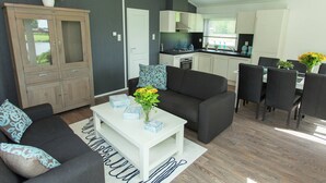 A modern living room with a sofa, coffee table, and a dining area with chairs and a table. - Comfortable Chalet With Dishwasher (IJhorst)