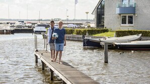 Eine Holzstele, die sich in ruhiges Wasser erstreckt, mit Booten, die in der Nähe liegen.