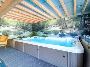 A hot tub with a waterfall mural, a wicker chair, and a wooden ceiling. - Spacious Holiday Home in Malmedy near Nature Parc High Venn (Malmedy)