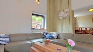 Ett modernt vardagsrum med en beige lädersoffa, ett soffbord i trä och en hängande lampa.