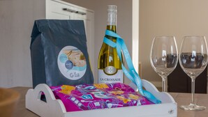 A bottle of wine, two glasses, and a gift bag on a table. - Holiday Home in Oostkapelle Near Beach (Oostkapelle)