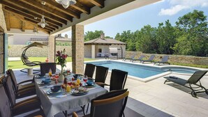 An outdoor dining area with a pool and lounge chairs. - Lovely Holiday Home With Private Pool (Svetvincenat)