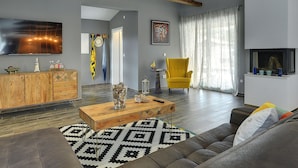 A modern living room with a wooden ceiling, a flat-screen TV, a yellow armchair, and a patterned rug. - Lovely Holiday Home With Private Pool (Svetvincenat)