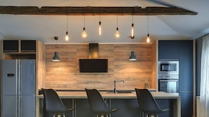 A modern kitchen with a wooden backsplash, a built-in oven, and a large island with bar stools. - Lovely Holiday Home With Private Pool (Svetvincenat)