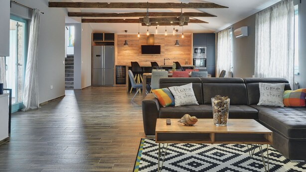 A modern living room with exposed wooden beams, a black leather sofa, a wooden coffee table, and a patterned rug. - Lovely Holiday Home With Private Pool (Svetvincenat)