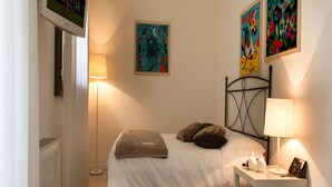 A bedroom with a bed, bedside table, lamp, and abstract paintings on the wall.