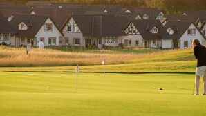 Una hilera de casas tradicionales de estilo europeo, con un campo de golf al frente.