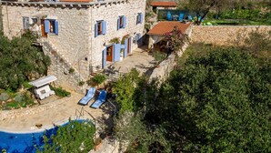 Una villa de piedra con piscina, mobiliario exterior y vistas del paisaje circundante.