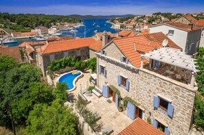 Un edificio in pietra con piscina, immerso in una zona residenziale e un porto turistico.