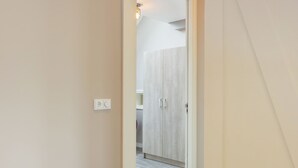 A narrow hallway with a wooden wardrobe and a light switch on the wall. - Holiday Home in Oostkapelle Near Beaches (Oostkapelle)