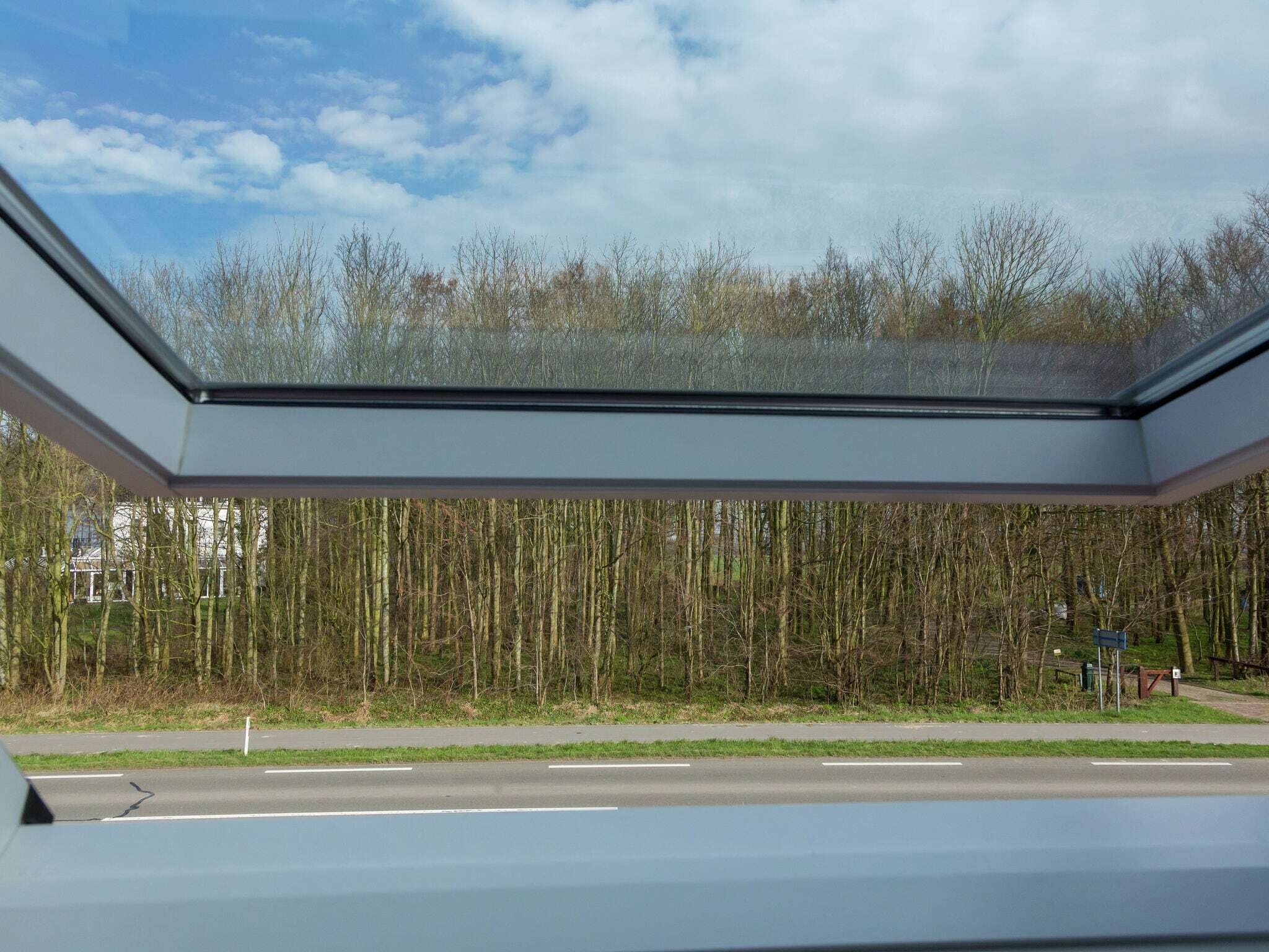 A view through a skylight with a road and trees in the background.