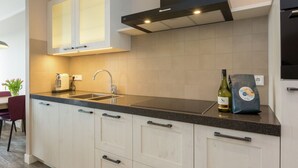 A modern kitchen with white cabinetry, a black countertop, and a stainless steel sink. - Holiday Home in Oostkapelle Near Beaches (Oostkapelle)