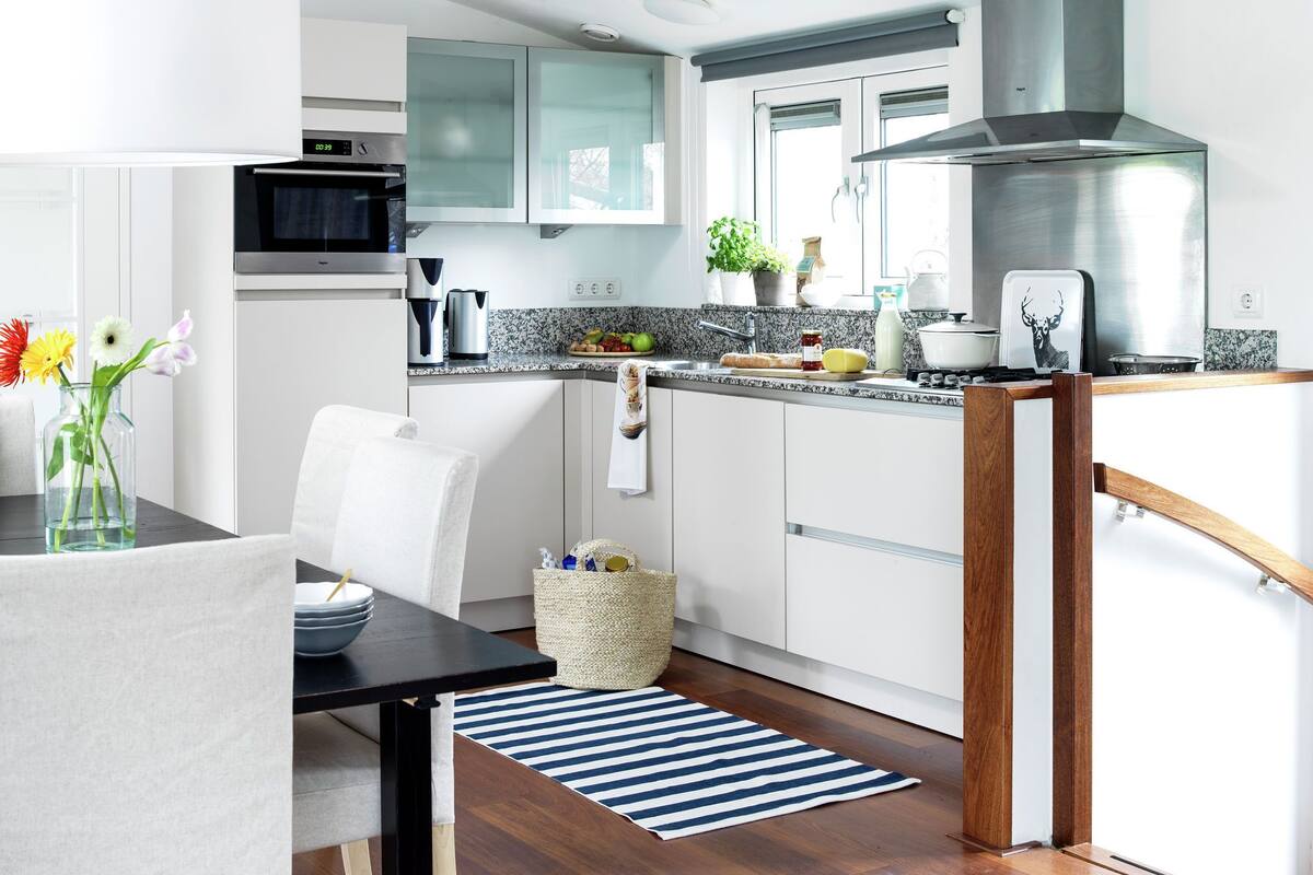 A modern kitchen with white cabinets, a stainless steel range hood, and a granite countertop.