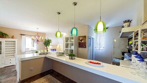 Una cocina moderna con una isla central, luces colgantes y una estantería empotrada para vinos.