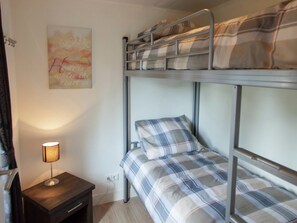 Dormitorio con literas, una mesita de noche y una l ámpara.