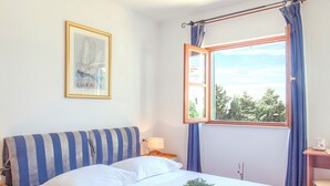 A bedroom with a bed, a window with curtains, a bedside table, and a framed picture on the wall. - Beautiful Villa With Spacious Terrace and Private Swimming Pool, on the Croatian Island of Hvar (Hvar)