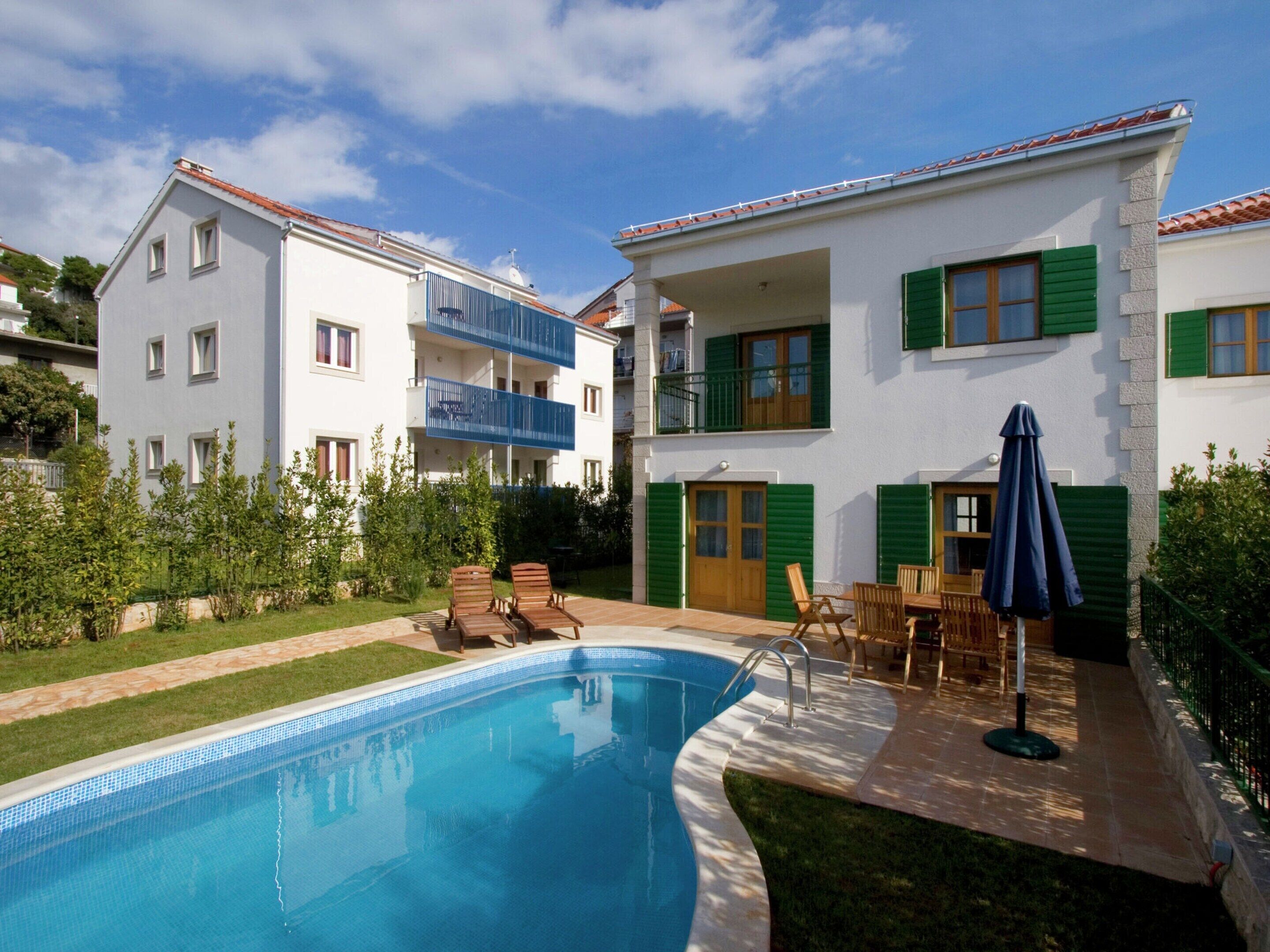 Un edificio residencial con piscina, zona de estar al aire libre y jardín.
