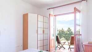 A bedroom with a bed, a wardrobe, and a balcony with a chair and table. - Beautiful Villa With Spacious Terrace and Private Swimming Pool, on the Croatian Island of Hvar (Hvar)