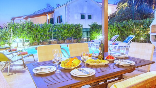 An outdoor dining area with a pool, lounge chairs, and a wooden pergola. - Beautiful Villa With Spacious Terrace and Private Swimming Pool, on the Croatian Island of Hvar (Hvar)