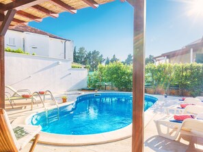 A swimming pool with lounge chairs and a pergola overhead. - Beautiful Villa With Spacious Terrace and Private Swimming Pool, on the Croatian Island of Hvar (Hvar)
