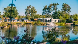 A lakeside hotel with modern buildings, a central fountain, and lush greenery. - Comfortable Chalet in the Green Kempen (Mol)
