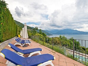 A terrace with sun loungers and umbrellas overlooking a lake and mountains. - Residential Complex With Panoramic Views and Pool (Oggebbio)