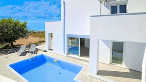 A modern white building with a swimming pool, a beach view, and a large window. - New Beautiful Villa With Private Pool at Coastal Area Just Outside Rethymno, NW (Apokoronas)