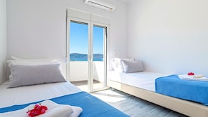 A hotel room with two beds, a balcony with a view, and an air conditioning unit. - New Beautiful Villa With Private Pool at Coastal Area Just Outside Rethymno, NW (Apokoronas)