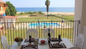 Ein Esstisch für vier Personen, gedeckt mit Geschirr, mit Blick auf Pool und Strand.