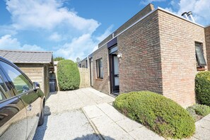 Un bâtiment moderne en briques, avec une voiture garée devant.