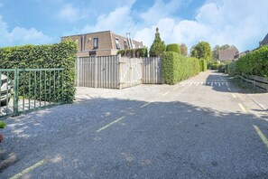 Une allée menant à une maison, avec une clôture en bois et un portail vert.