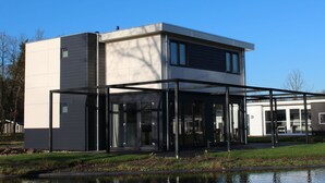 A modern two-story house with a covered patio area. - Luxury Villa With Three Bathrooms, Near a National Park (IJhorst)