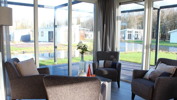 A modern living room with large windows, two sofas, a coffee table, and a vase with flowers. - Luxury Villa With Three Bathrooms, Near a National Park (IJhorst)