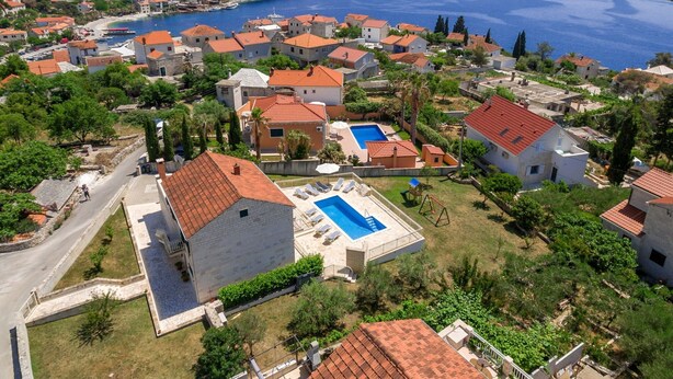 A coastal residential area with houses, a swimming pool, and a view of the sea. - Villa in Sumartin Near the Beach & Ferry Port (Selca)
