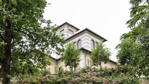 Een gebouw met twee verdiepingen, een stenen muur en een tuin met roze bloemen.