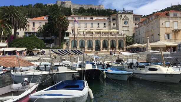 A marina with boats docked, a historic building with arches, and a castle in the background. - Charming Villa With Spacious Rooms and Private Swimming Pool in the Lavender Island of Hvar (Hvar)