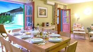 A dining area with a table set for four, a painting on the wall, and a view of a swimming pool outside. - Charming Villa With Spacious Rooms and Private Swimming Pool in the Lavender Island of Hvar (Hvar)