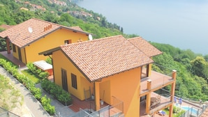 A yellow villa with a red-tiled roof, a balcony, and a view of a lake and mountains. - Residential Complex With Panoramic Views and Pool (Oggebbio)