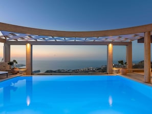 A modern infinity pool with a clear view of the sea and distant buildings. - Luxury Villa With Heated Pool in Agia Pelagia (Malevizi)