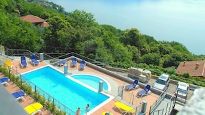 A swimming pool with lounge chairs, surrounded by greenery and a view of a lake and mountains. - Residential Complex With Panoramic Views and Pool (Oggebbio)