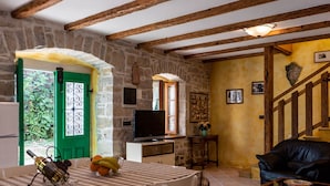 Ein rustikaler Innenraum mit Essbereich, Fernseher und Treppe.