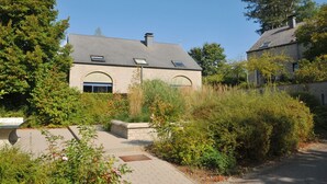 A two-story house with a sloped roof, a small attached garage, and a paved driveway. - Modern Apartment in Belgium With Bubble Bath (Durbuy)