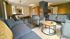 A modern living room with a sofa, chairs, a coffee table, and a fireplace. - Modern Apartment in Belgium With Bubble Bath (Durbuy)
