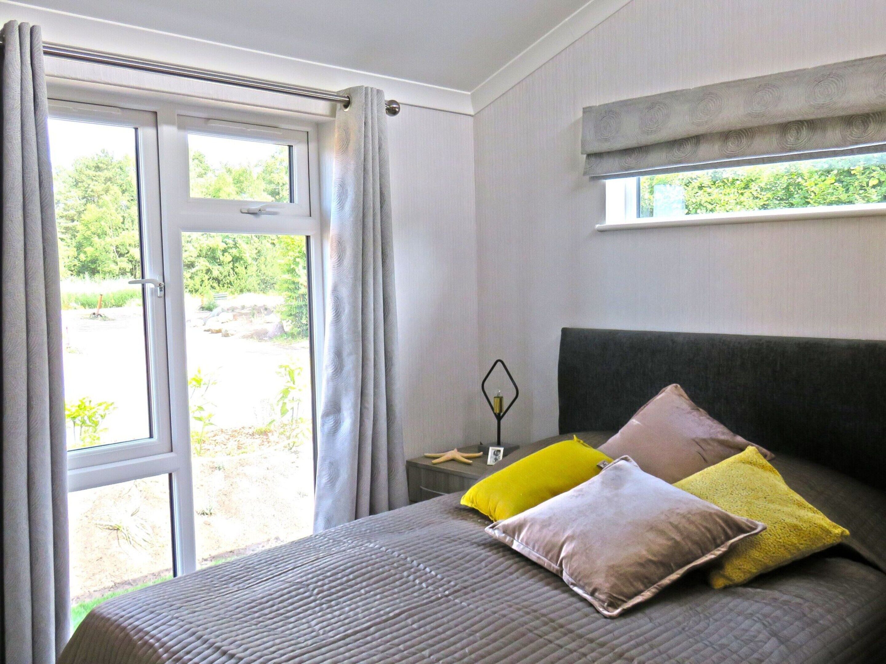A bedroom with a bed, a window, and a view of greenery outside.