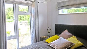 A bedroom with a bed, a window, and a view of greenery outside.