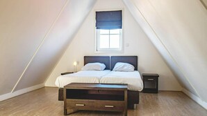 A bedroom with a bed, bedside tables, a window with a blind, and a sloped ceiling. - Holiday Home Built in Zaanse Style, Near Alkmaar (West-Graftdijk)