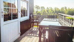 A deck with a glass table and chairs, wooden railings, and a view of trees. - Holiday Home Built in Zaanse Style, Near Alkmaar (West-Graftdijk)